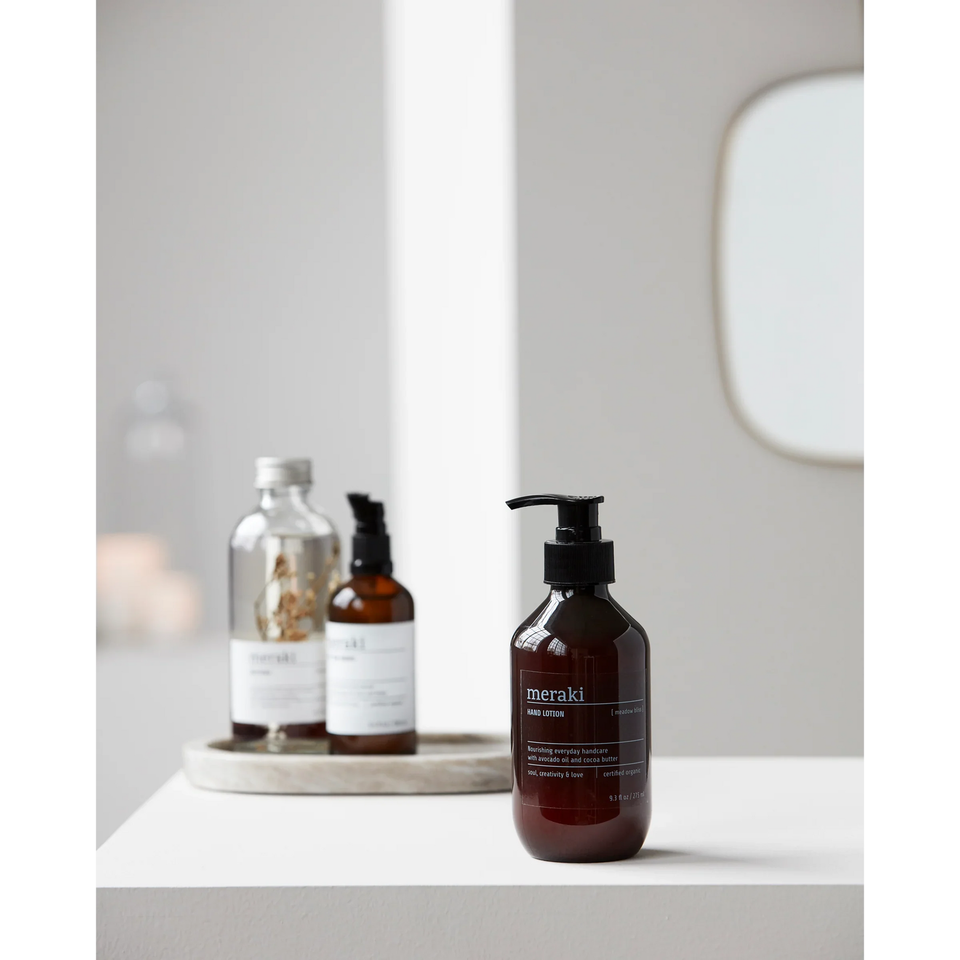 Meraki Meadow Bliss handlotion in een minimalistische badkameromgeving met spiegel en andere verzorgingsproducten