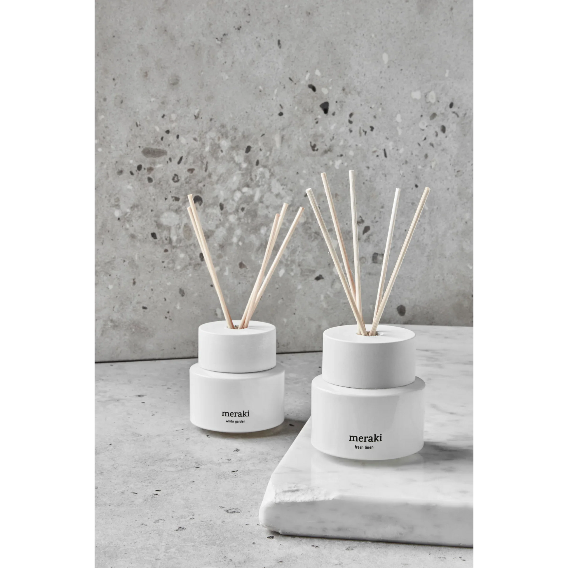 Twee Meraki White Garden diffusers samen gestyled op steenachtig oppervlak met natuurlijk licht