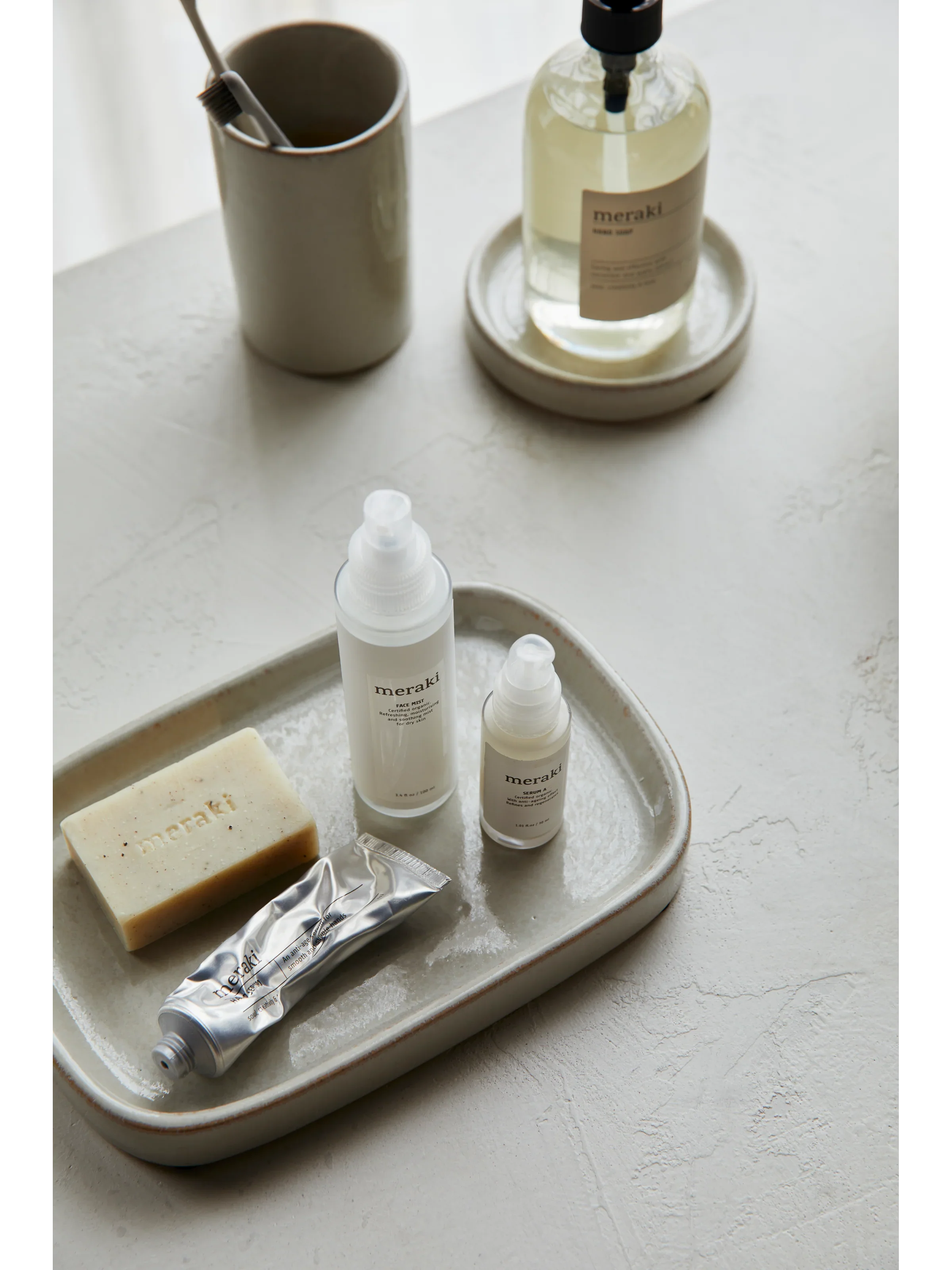 Meraki Silky Mist handzeep naast geurkaars en andere verzorgingsproducten op dienblad in luxe setting